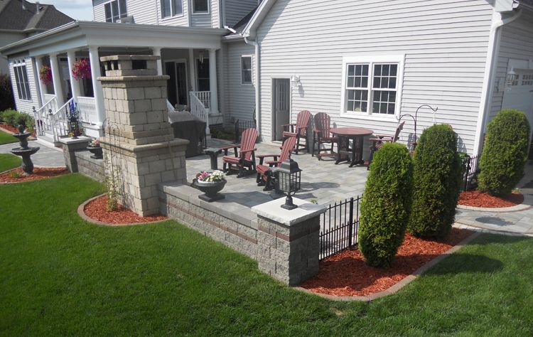 An outdoor fireplace is the centerpiece of this lovely side yard paver patio.