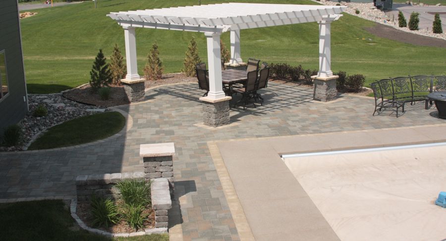 Columns for the base of the pergola were constructed with VERSA-LOK Standard retaining wall units in Bronze Blend with a weathered texture. For patio surfaces, Willow Creek Paving Stones Slatestone pavers in Bleu with a sandstone border look beautiful whether the pool is open or covered.