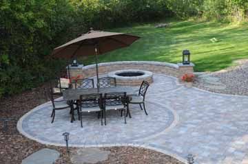 An outdoor dining area and firepit with seat wall make the landscape design more useful and enjoyable.