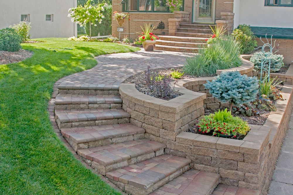 The curved walkway and staircase give the home great curb appeal and a graceful transition of the slope to the driveway. Planters created with VERSA-LOK retaining wall blocks add interest with curves, corners and stepped appearance as well as ample planting space for a bounty of plants and shrubs.